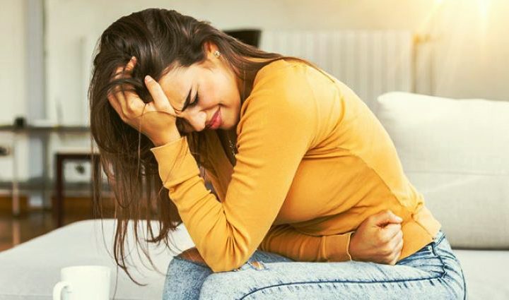 mujer con dolor por endometriosis sentada sujetando el abdomen