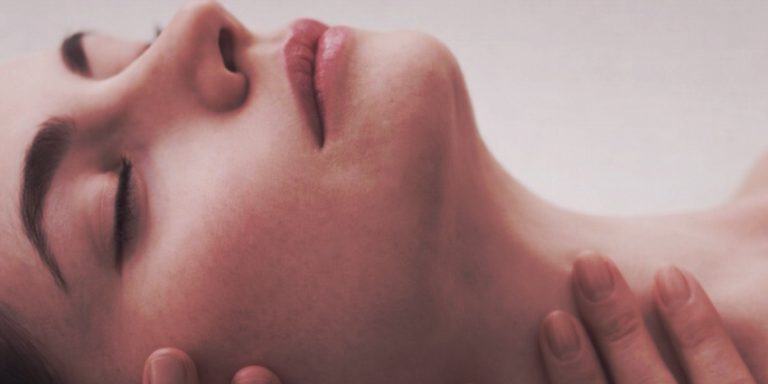 Mujer relajada con los ojos cerrados durante un momento íntimo en la perimenopausia